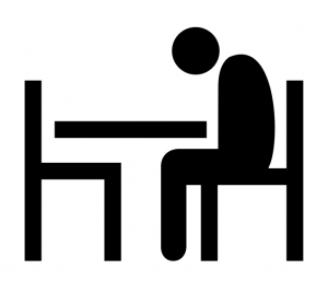 Picture of person sitting alone at a table with head bowed